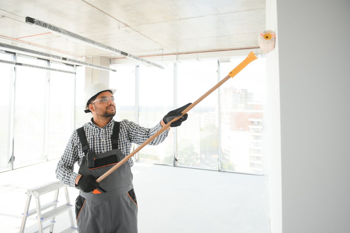 Commercial painter rolling a wall in a bright, empty office space